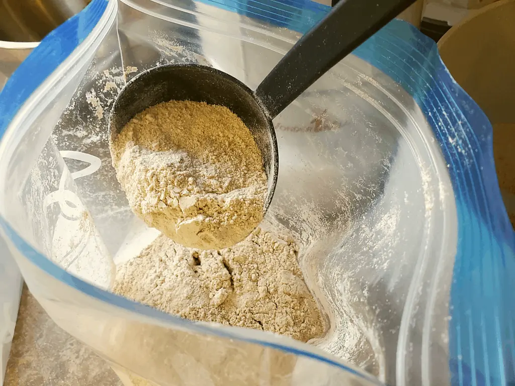 Placing sprouted wheat flour in a freezer safe bag with a ladle