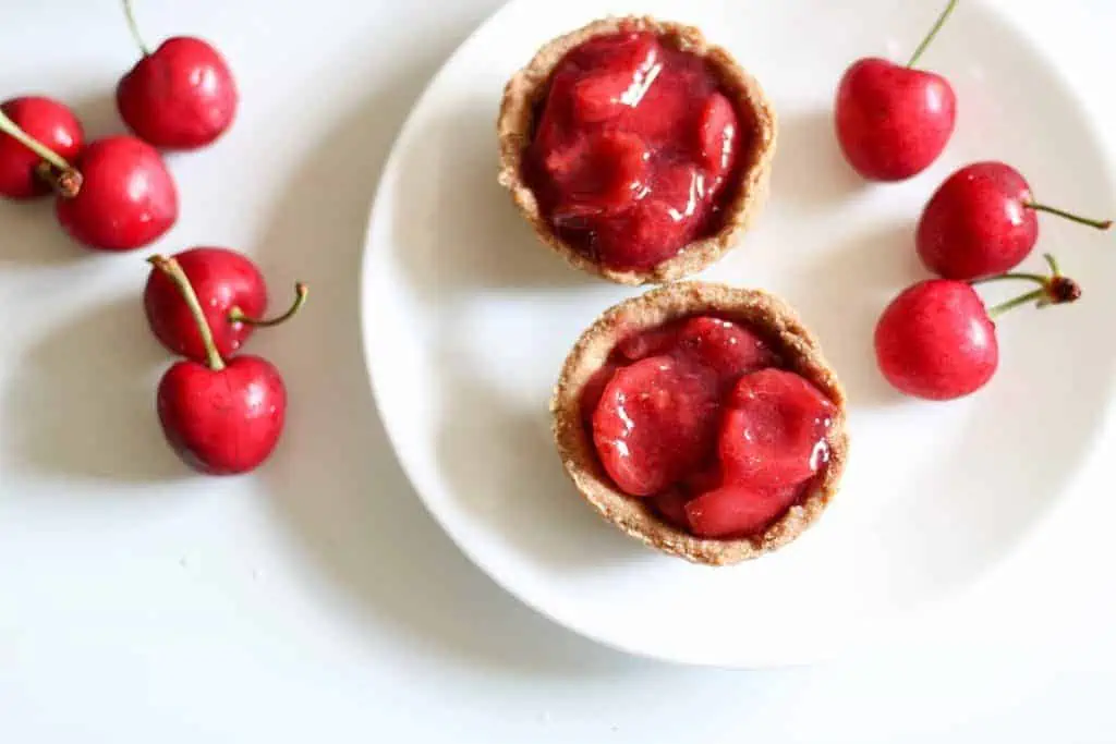 2 cherries tarts on a plate with fresh cherries