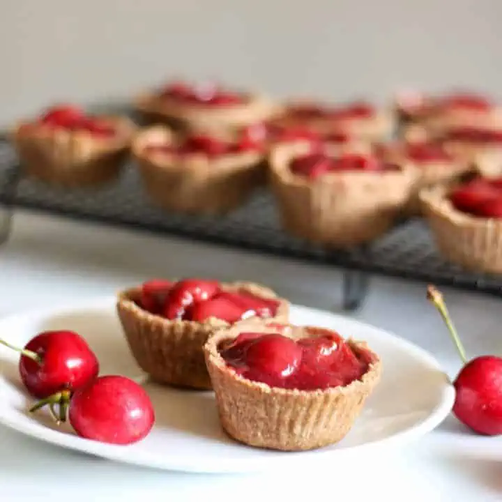 cherry tarts on plate with more behind them