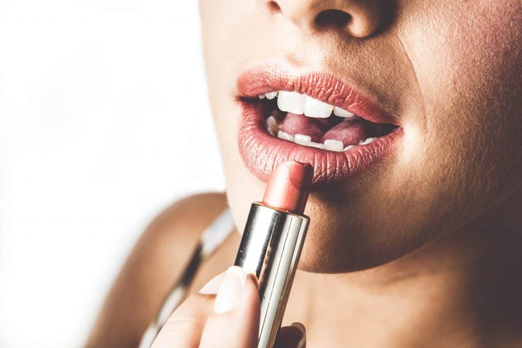 woman putting lipstick on