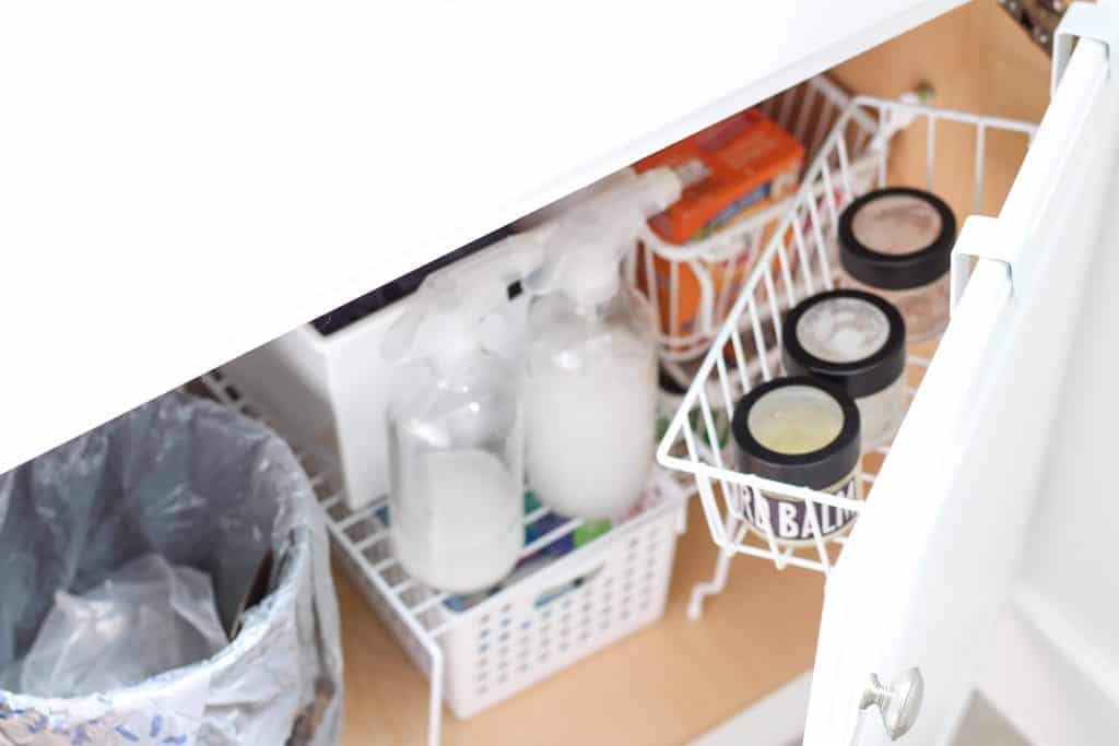 organized area under bathroom sink with shelves, baskets and over the door basket