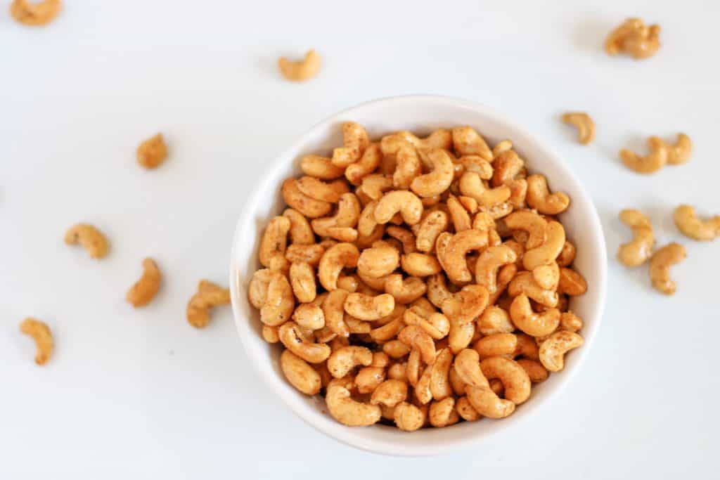 roasted cashews in a bowl with some more around