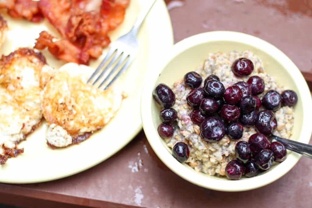 bowl of oatmeal with blueberries and eggs on the side