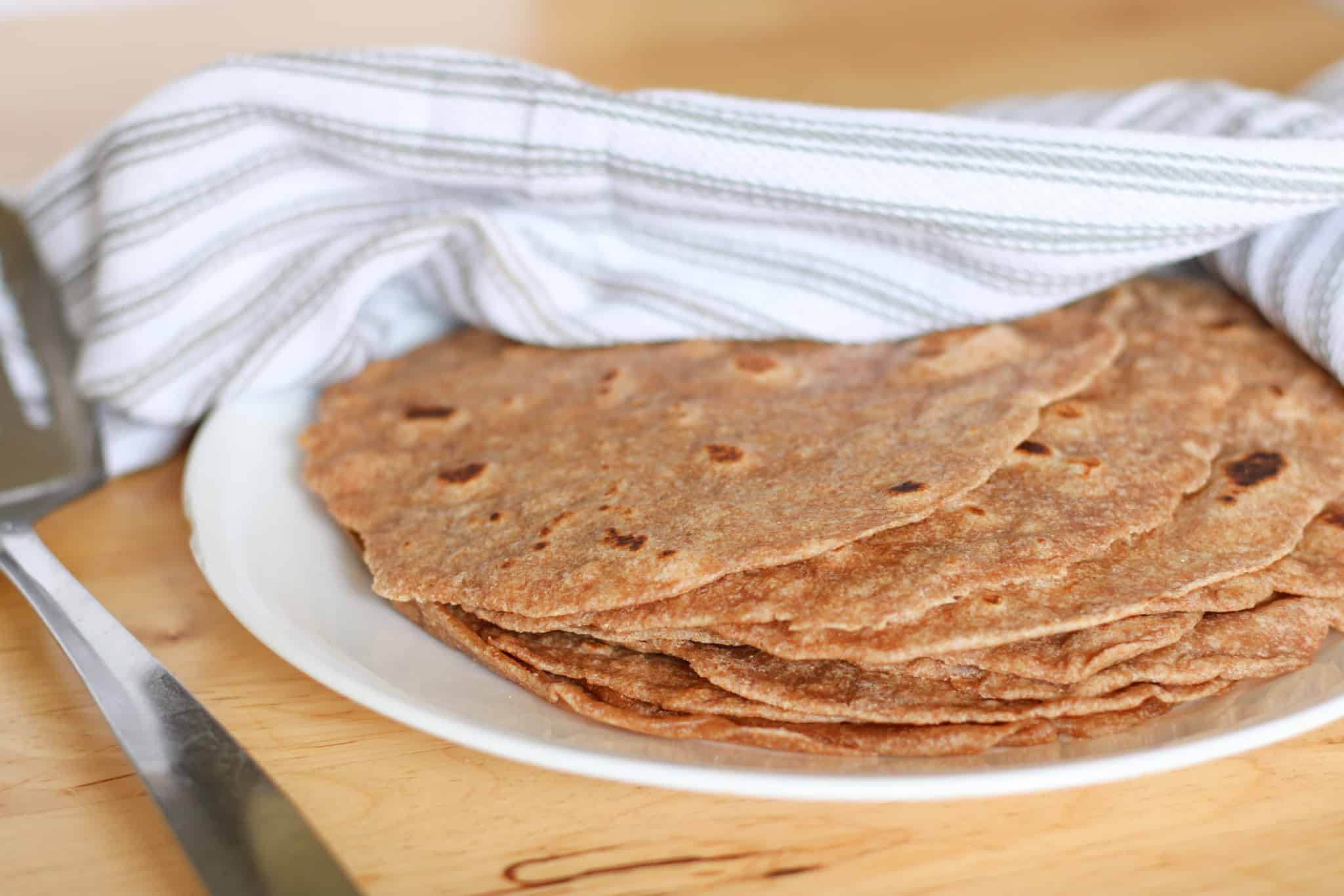 tortillas on plate covered with tea towel