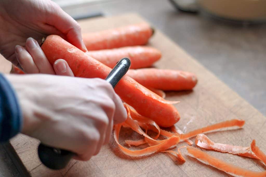 woman peeling carrots on a cutting board