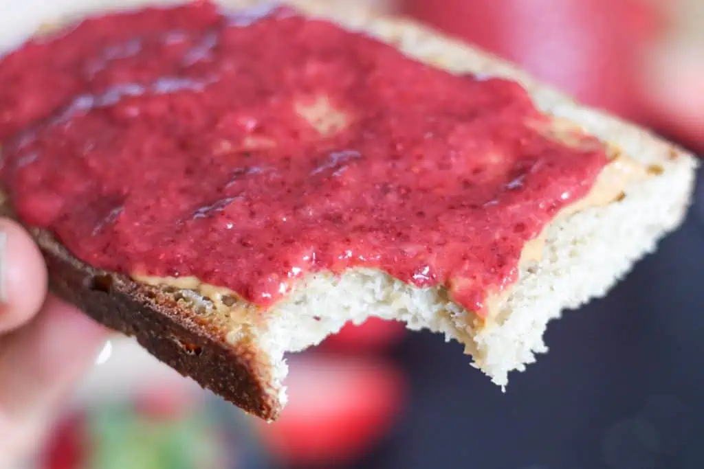 Piece of bread with peanut butter and low sugar strawberry jam