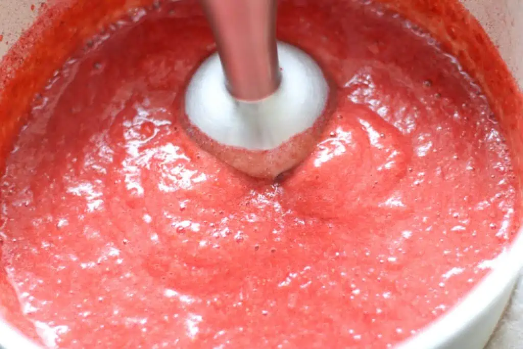 blending strawberry jam with an immersion blender