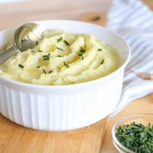 large bowl of mashed potatoes with spoon and chives