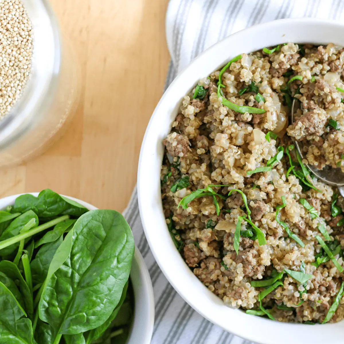 bowl of ground beef and quinoa, with dry quinoa and spinach on the side
