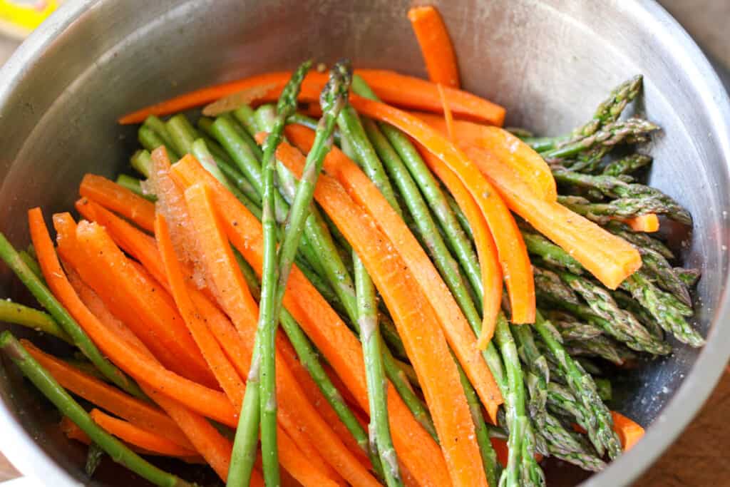 seasoned asparagus and carrots in a mixing bowl