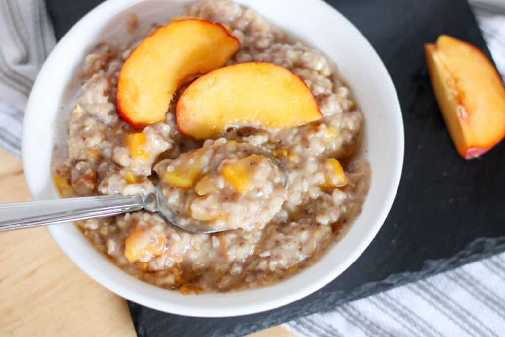 bowl of oatmeal topped with peach slices