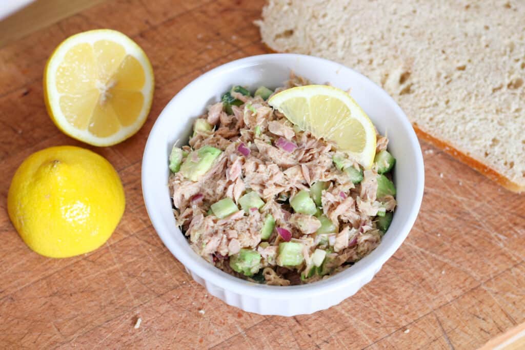bowl of tuna salad, lemons and bread