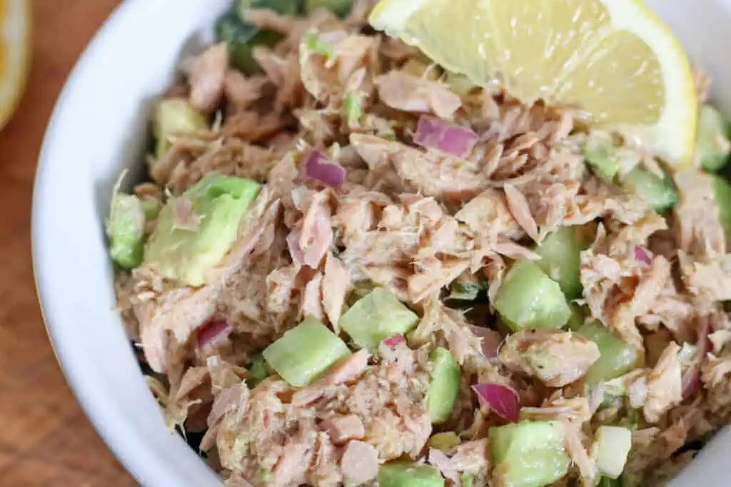close up of tuna salad with red onion, avocado and cucumber