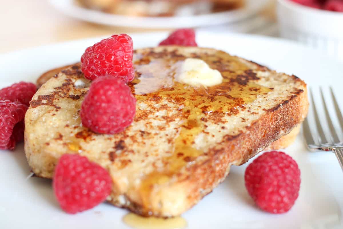 french toast with butter, syrup and raspberries