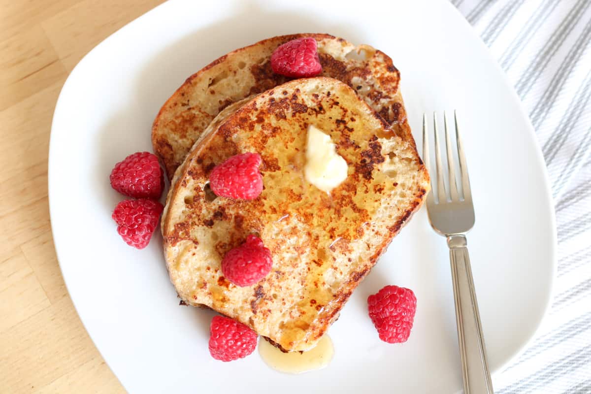 plate of french toast and raspberries with fork
