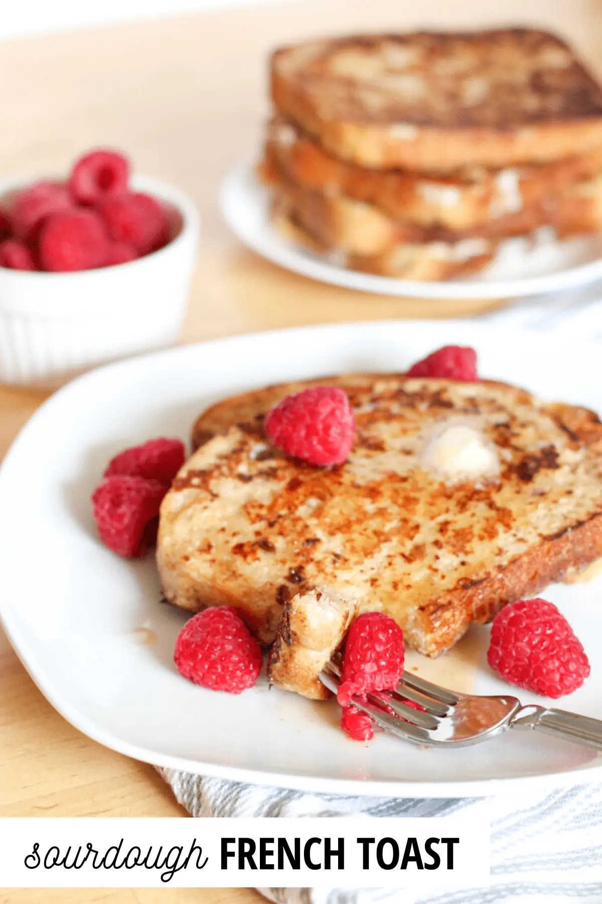 french toast and raspberries on a plate with a fork