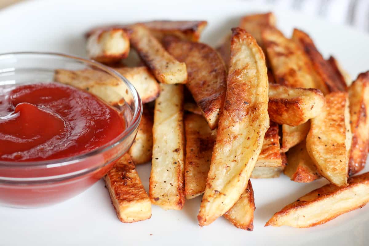 Potato fries on a plate with a small dish of ketchup