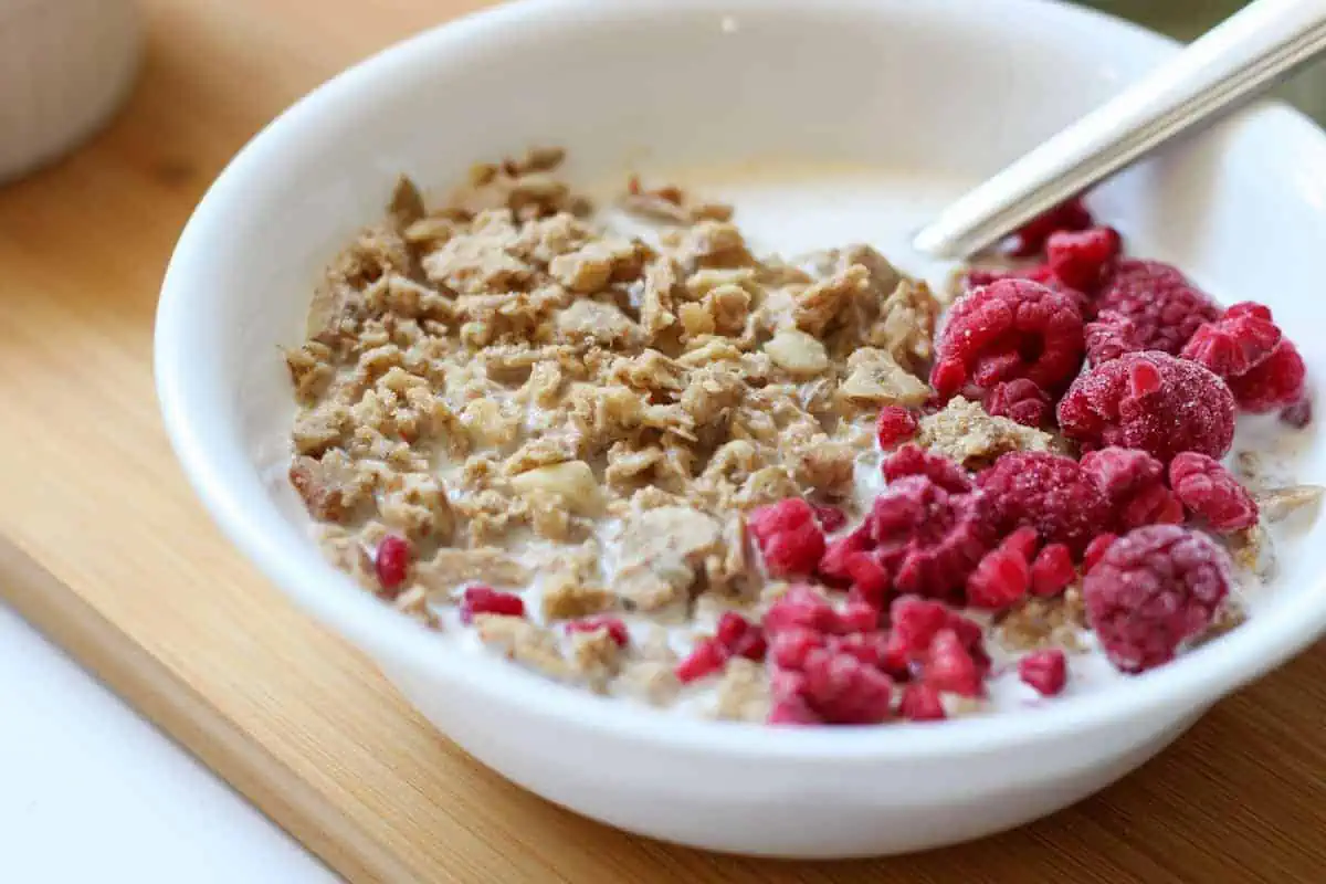 bowl of granola, milk and raspberries