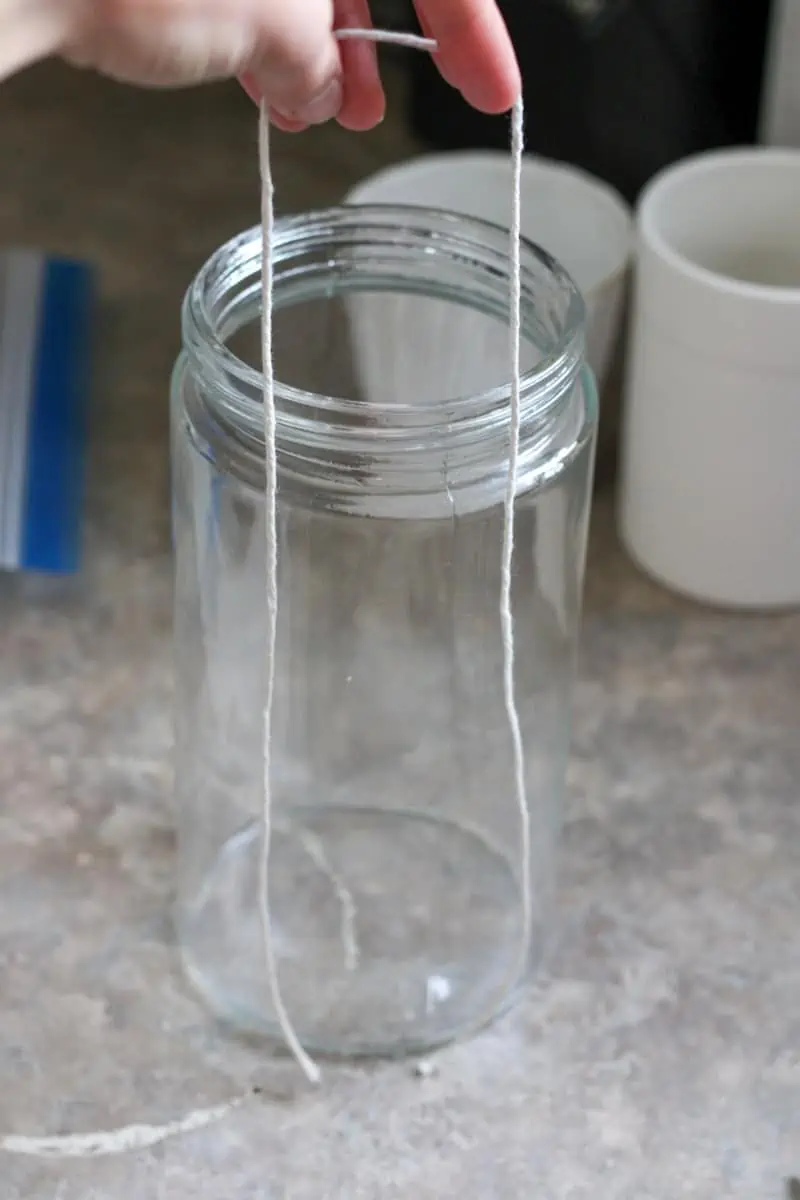 holding a string up to a tall jar