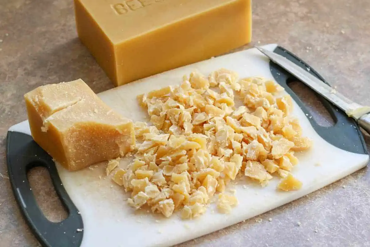cutting beeswax block into small pieces on cutting board