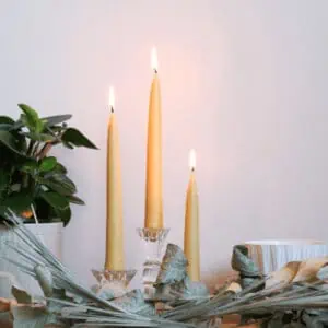 3 beeswax taper candles lit and styled