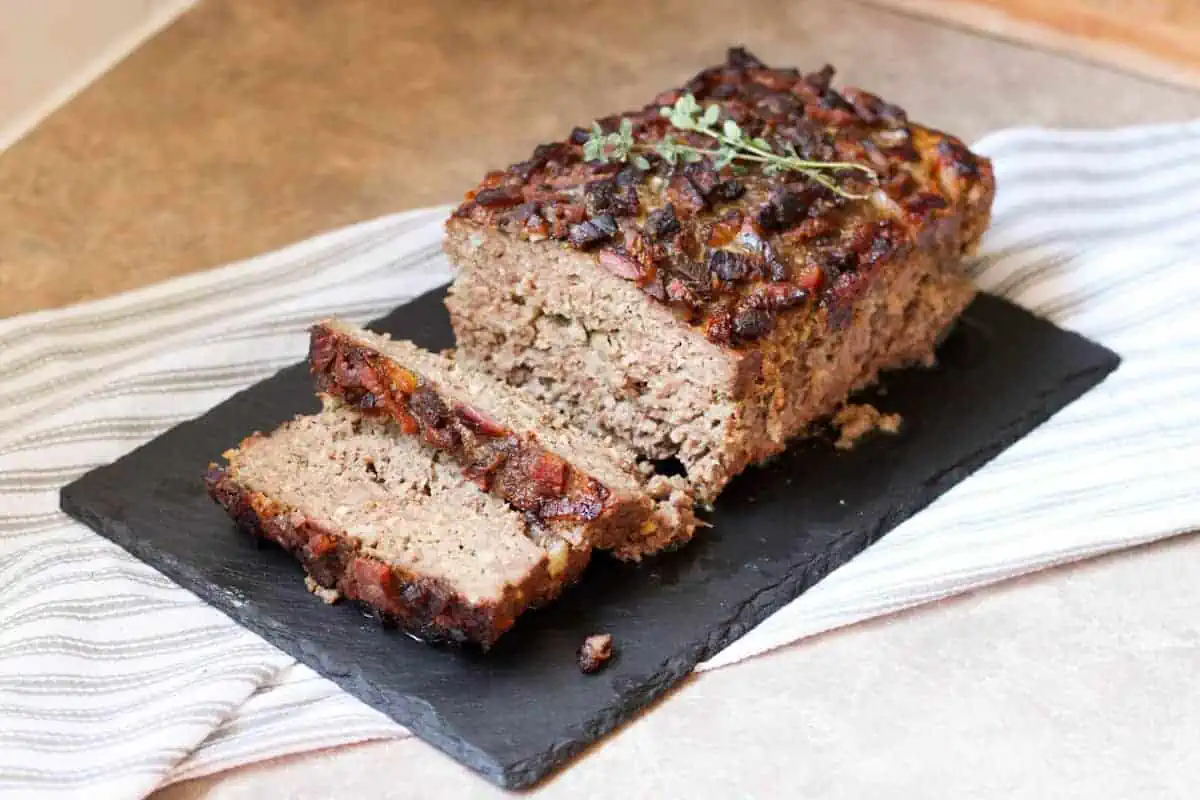 meatloaf with herbs on top and a few slices cut