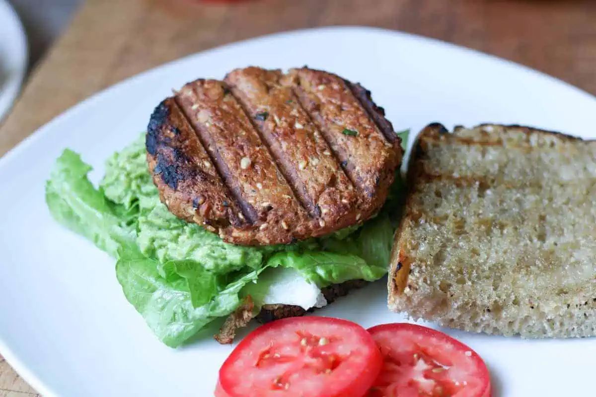 salmon burger with bread, lettuce, tomato and guacomole