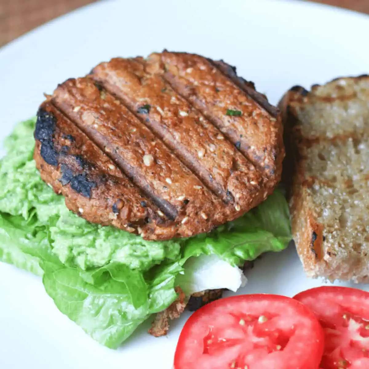 salmon burger on bread with lettuc, avocado and tomatoes