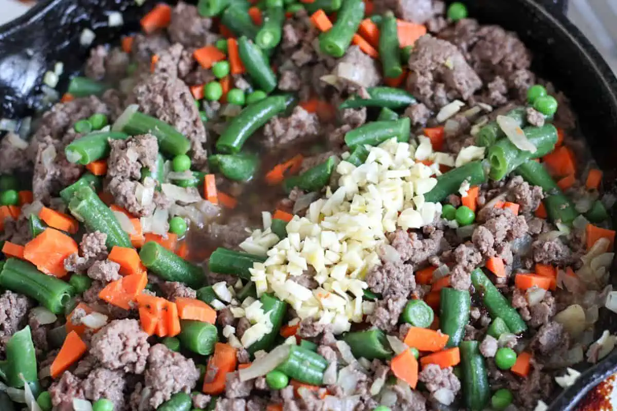 ground meat, vegetables and garlic mixed in a pan