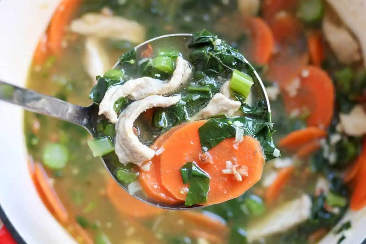 ladleful of soup with pork, chinese broccoli and carrots