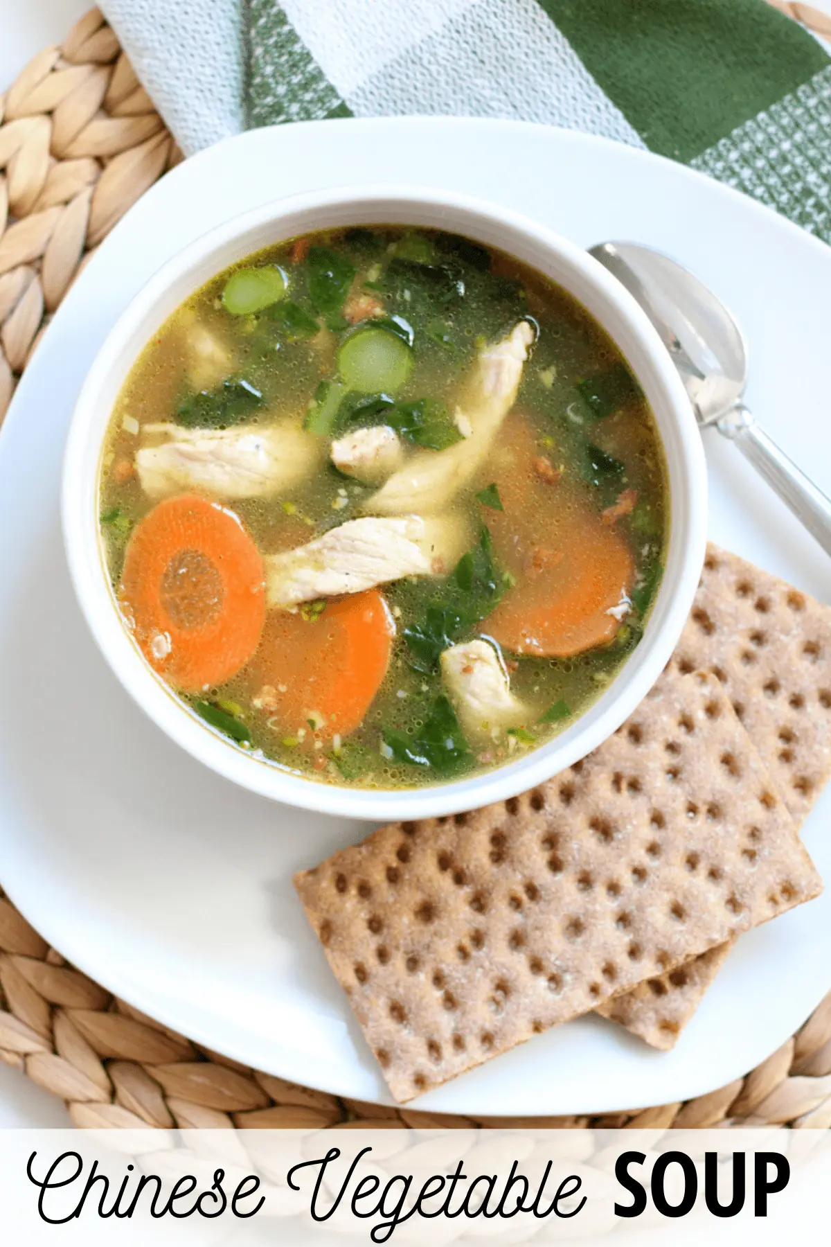 bowl of soup on a plate with crackers and a spoon