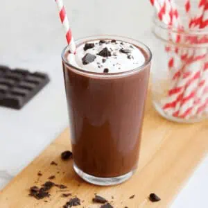 glass of chocolate milkshake topped with whipping cream and chocolate