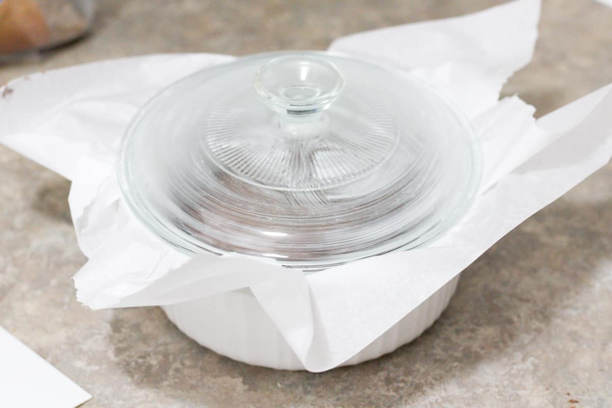 corningware dish with the lid on and parchment paper sticking out