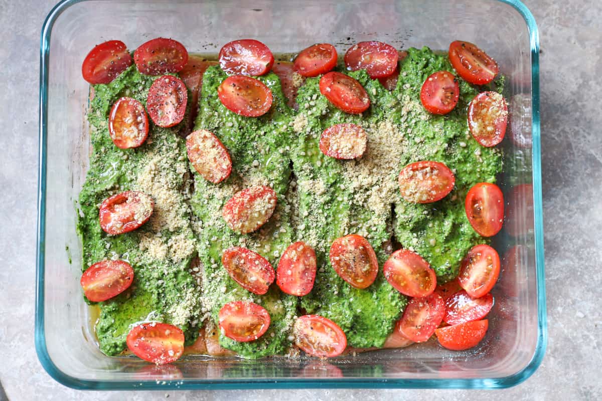 salmon, pesto, tomatoes and parmesan cheese in a glass dish
