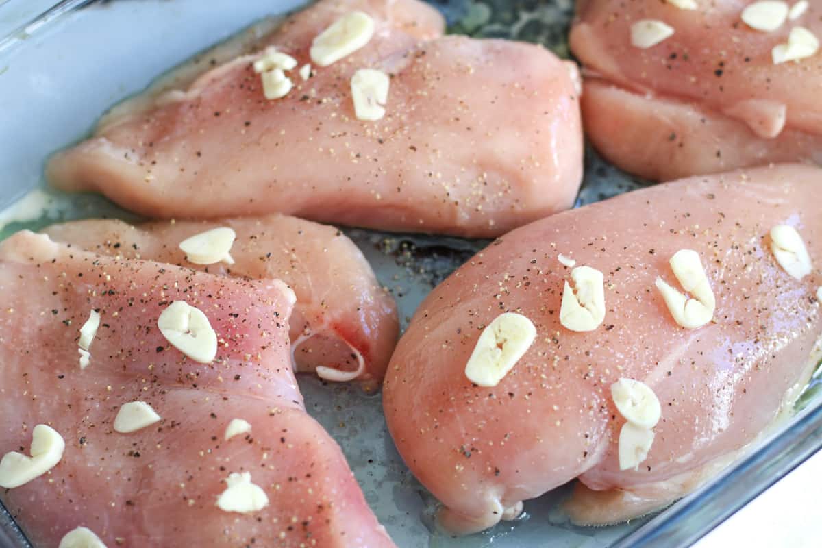 raw chicken breasts with garlic slices on top