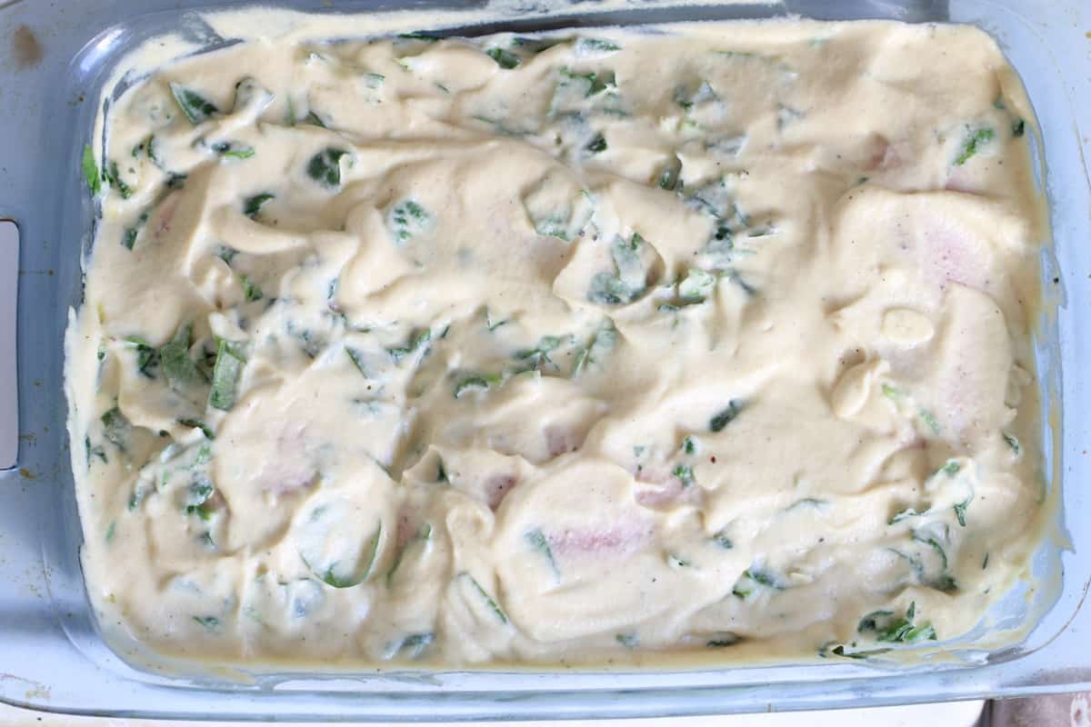 chicken in a pan topped with cream sauce