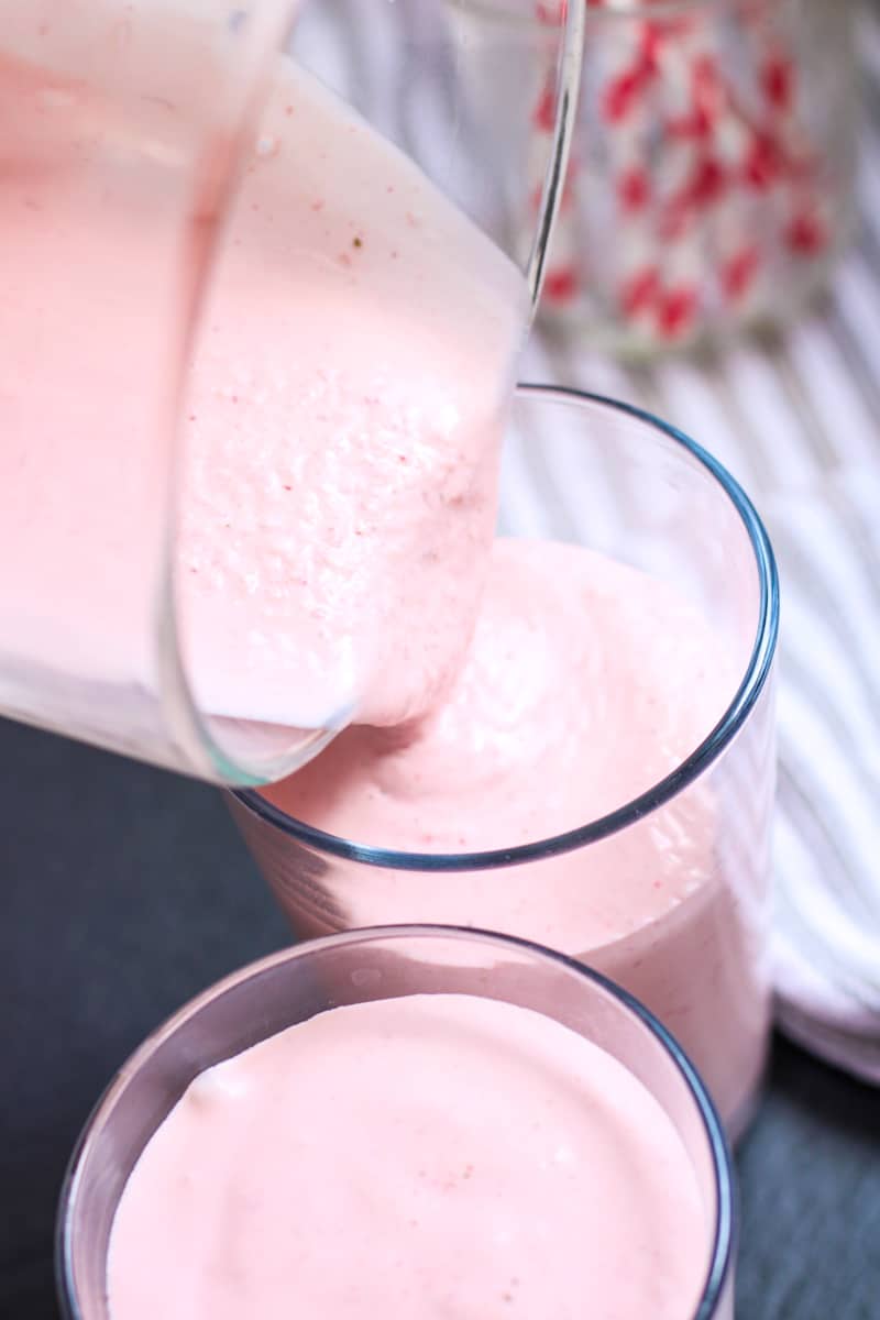 pouring strawberry milkshake into glasses