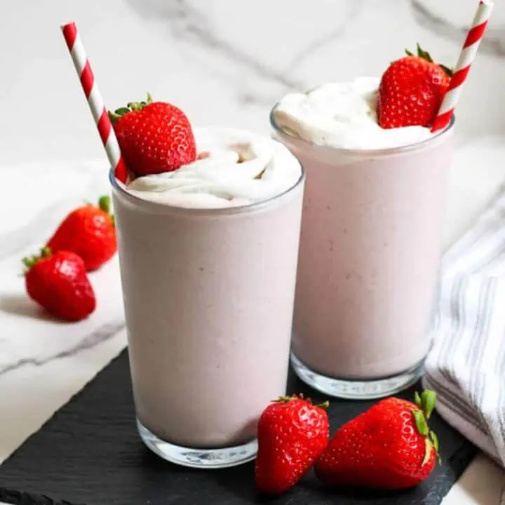 2 cups of strawberry milkshake with cream and strawberries