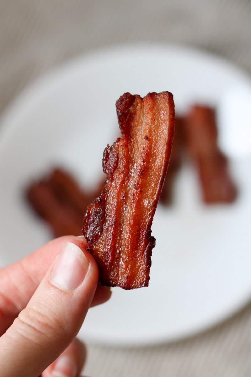 someone holding up one slice of bacon