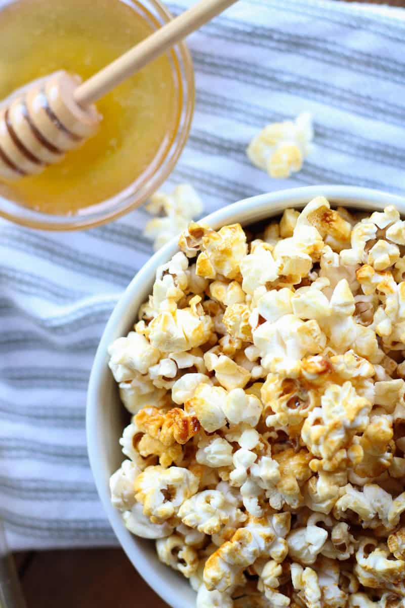 bowl of popcorn beside bowl of honey with drizzler
