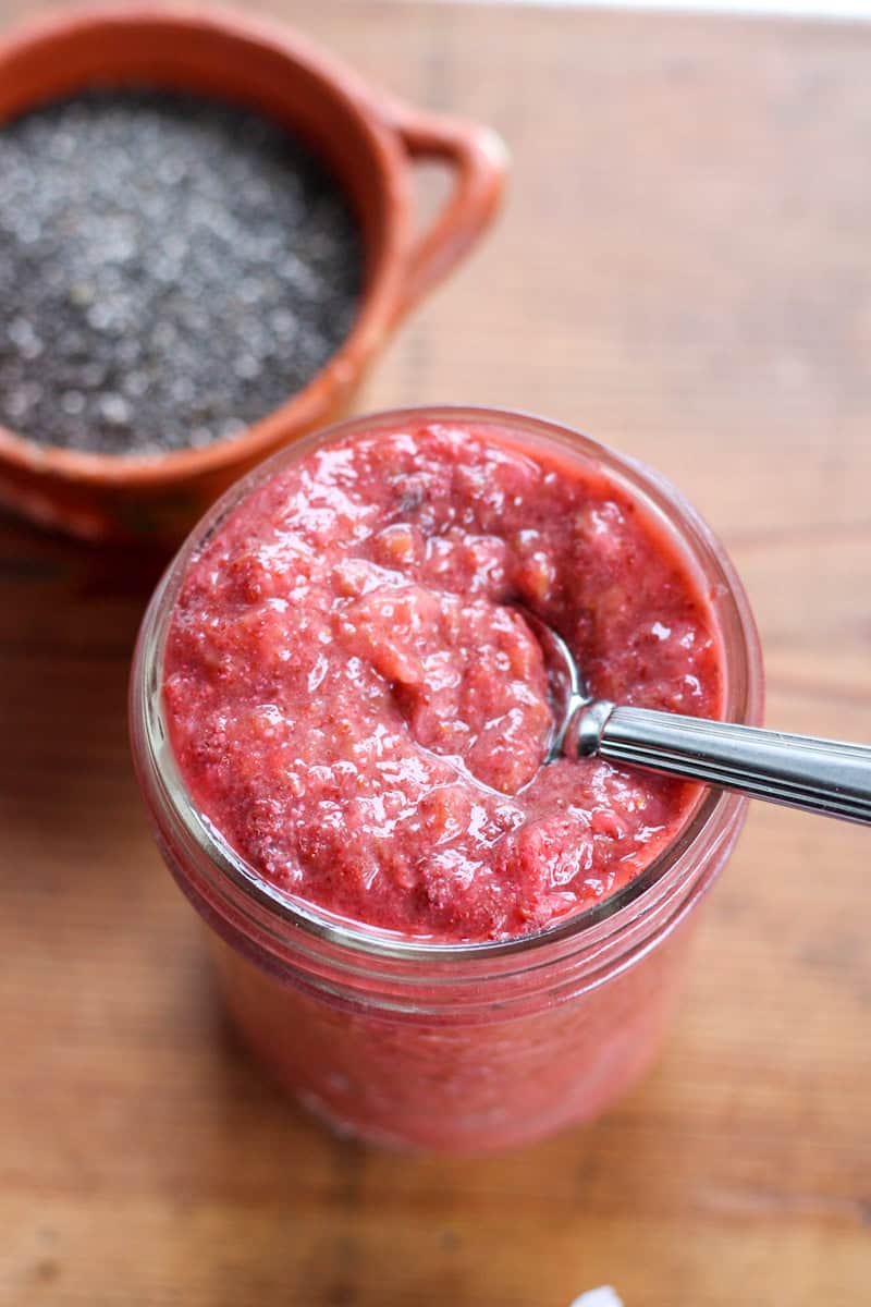 jar of strawberry rhubarb jam with bowl of chia seeds behind it
