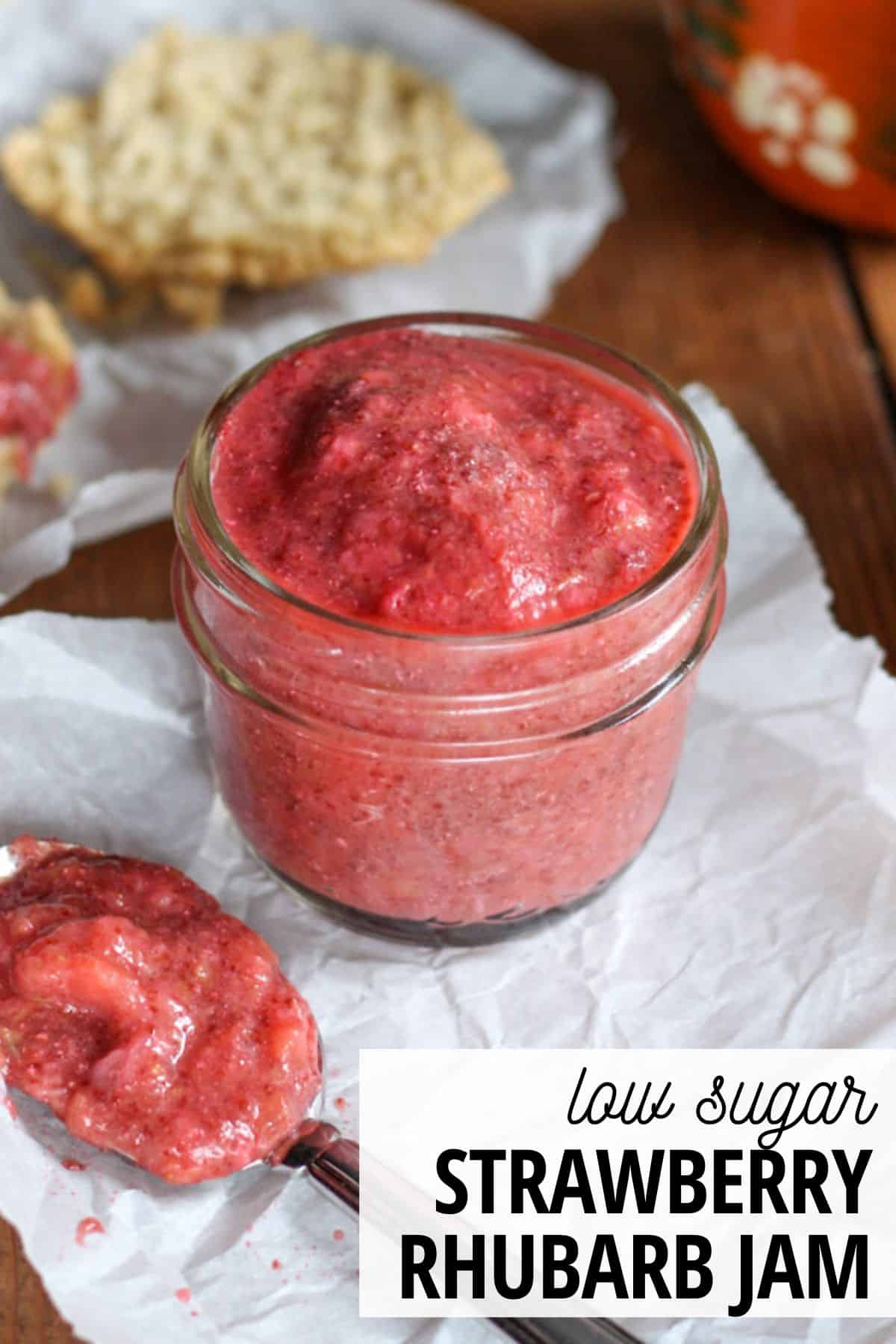jar of strawberry rhubarb jam with biscuits in the background