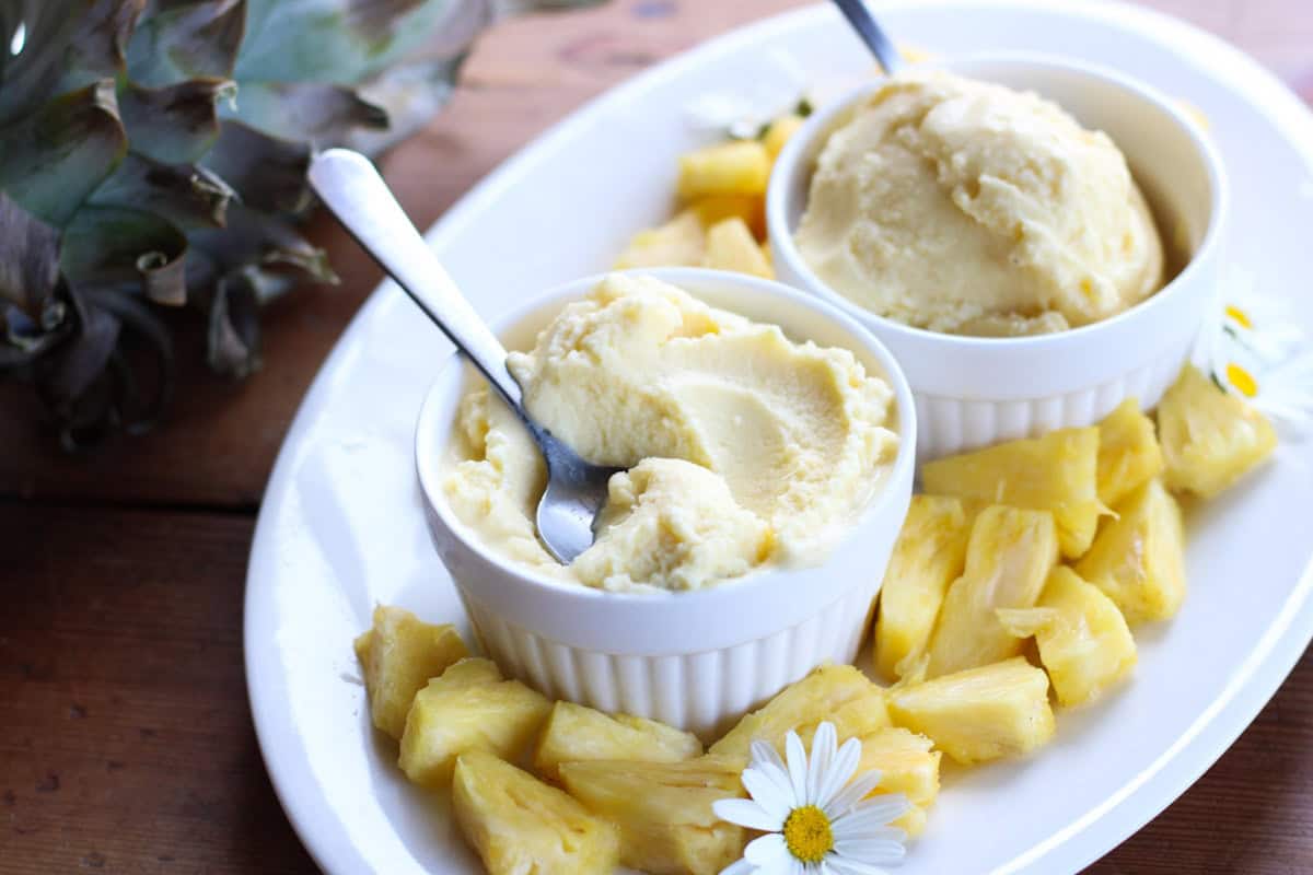 bowls of pineapple ice cream and pineapple around it